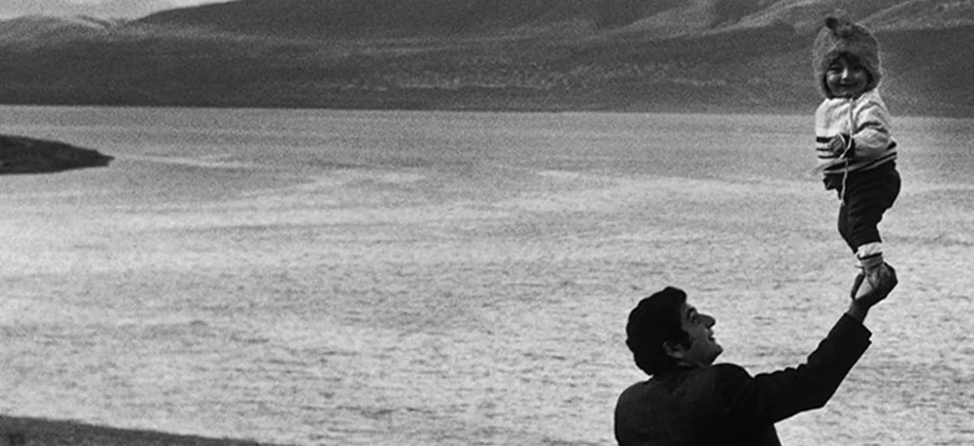 Pai brincando com o filho no ar, em fotografia antiga